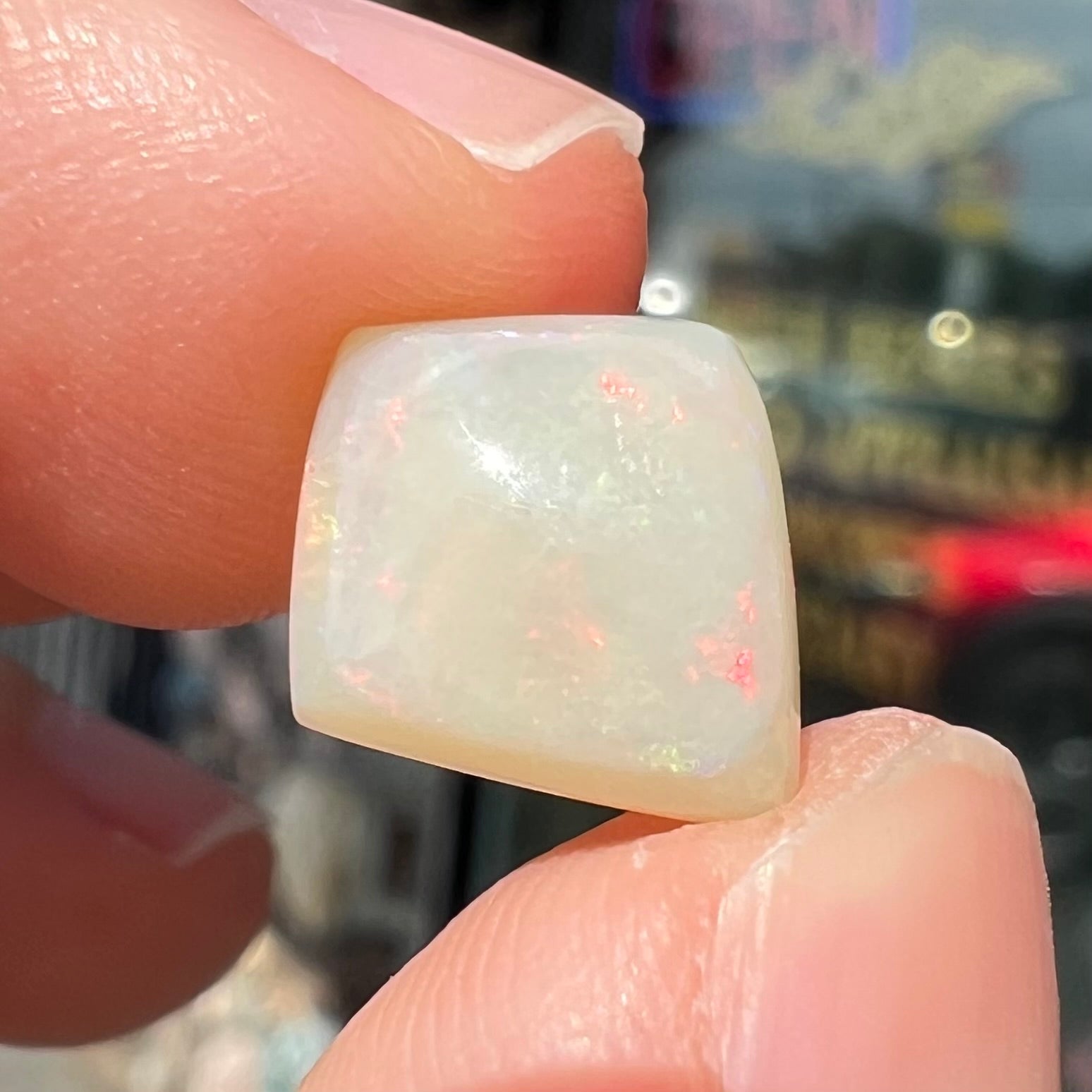 A loose, kite shaped white opal stone from Coober Pedy, Australia.  The stone has subdued red colors.