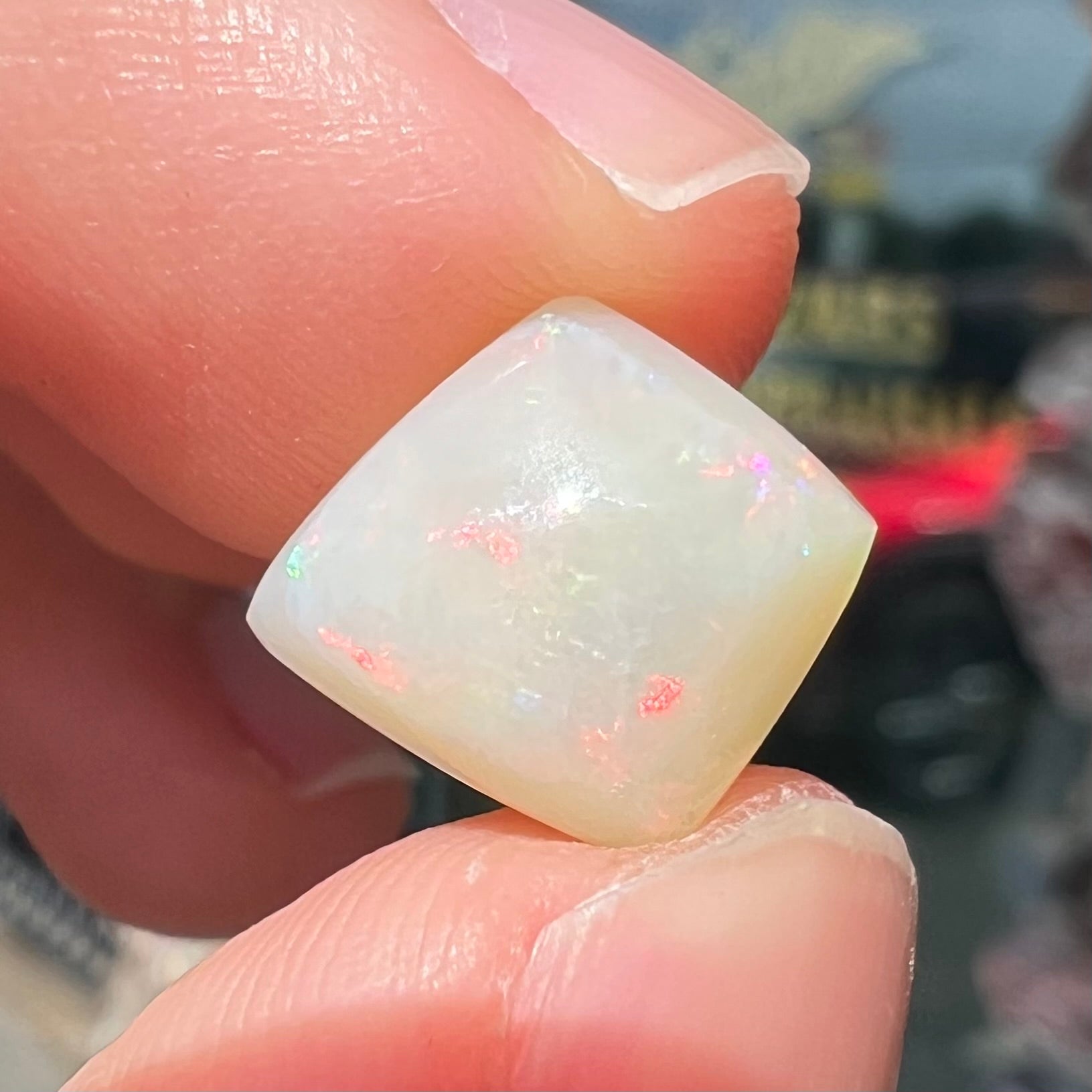 A loose, kite shaped white opal stone from Coober Pedy, Australia.  The stone has subdued red colors.