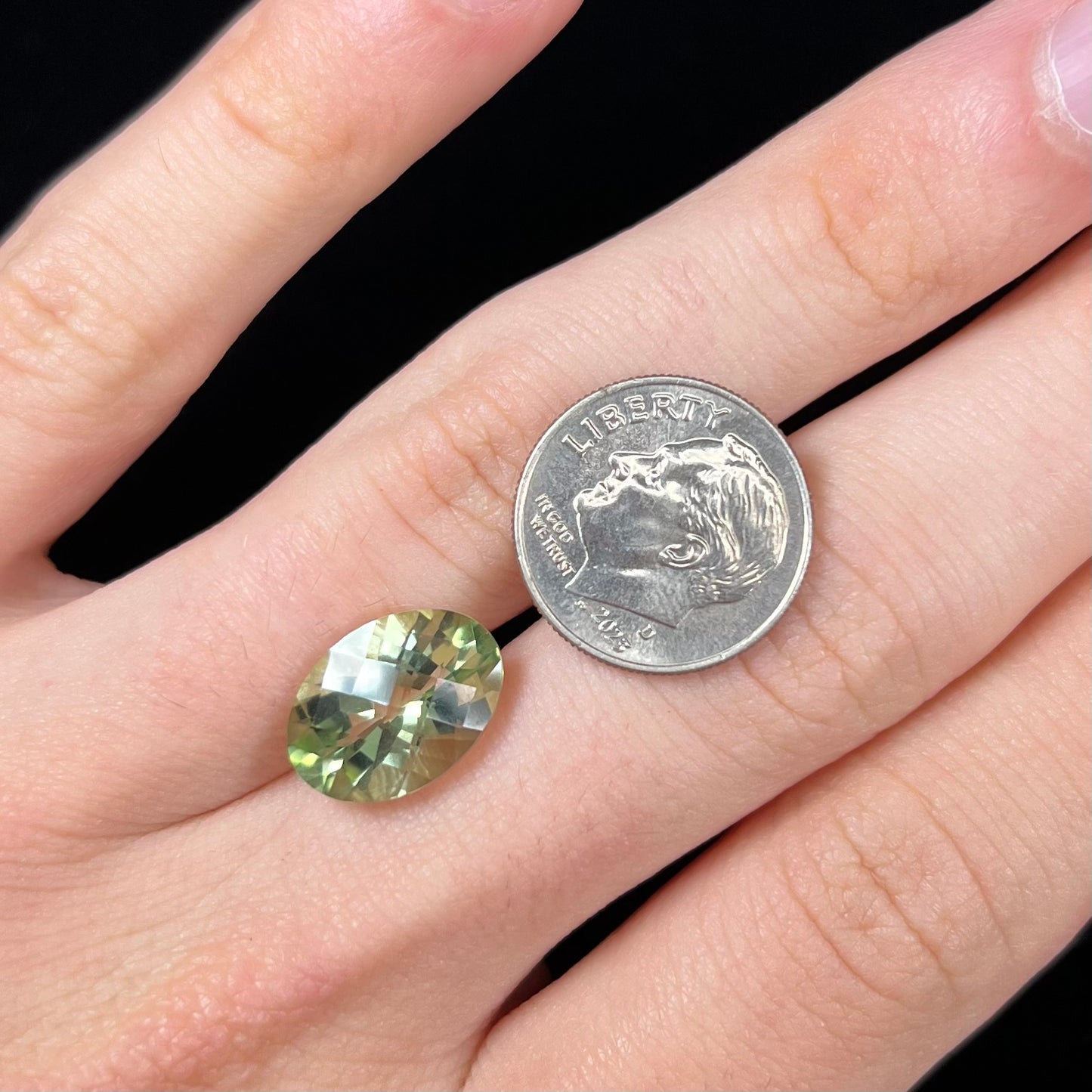 An oval checkerboard cut kiwi mystic topaz gemstone.  The stone is a light yellowish green color.