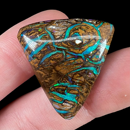 A triangle shaped Koroit boulder opal.  The stone has blue veins of opal running through it.