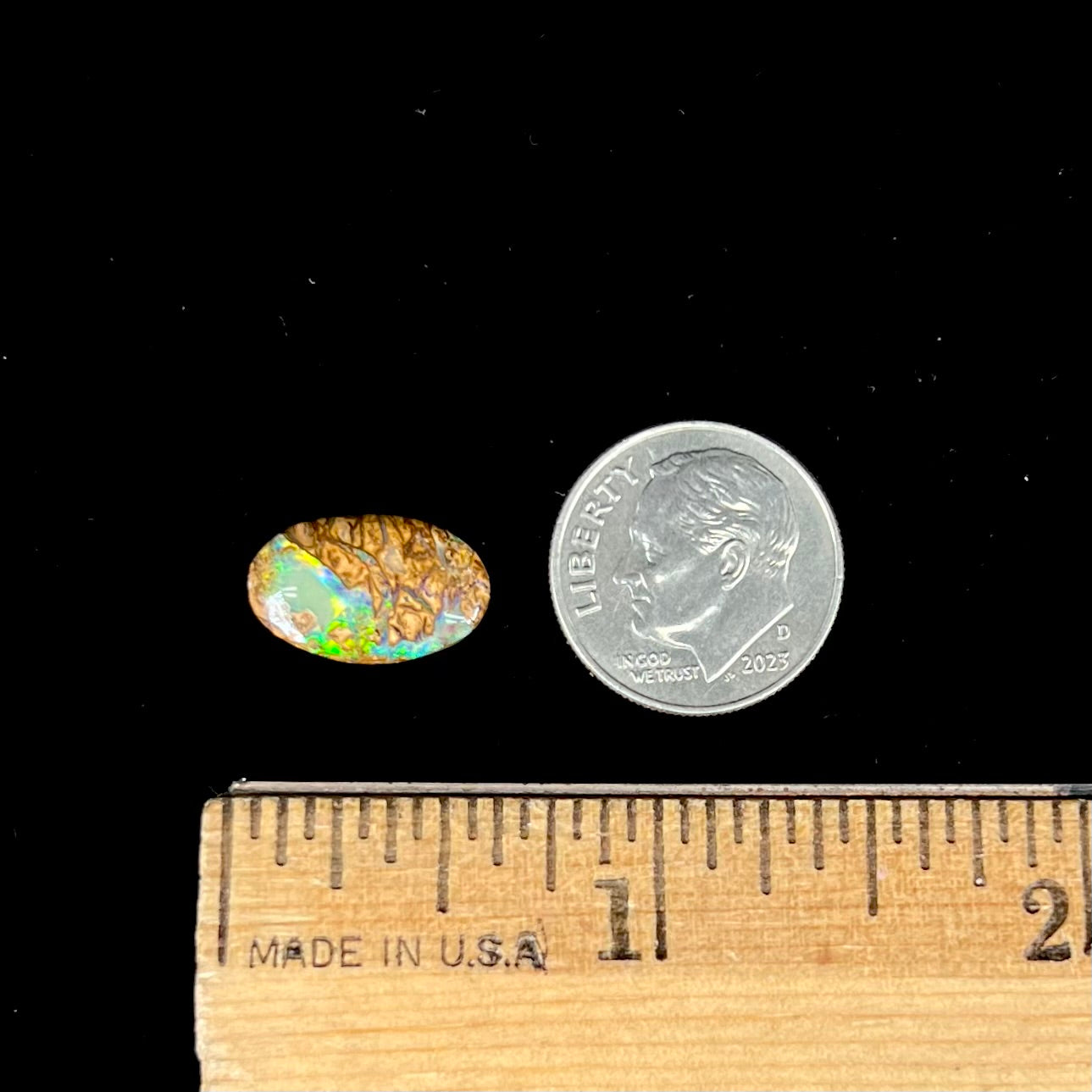 A loose, oval cabochon cut Koroit boulder opal with green fire.