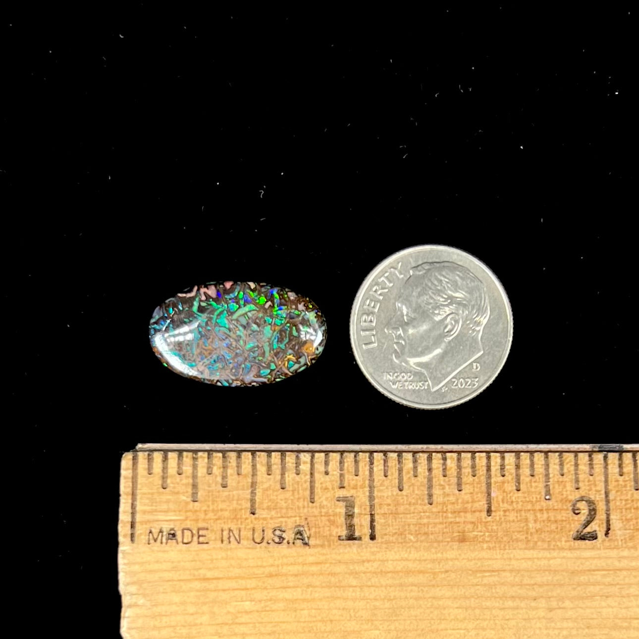 A loose, oval cabochon cut Koroit boulder opal stone.  The opal has green and blue veins.