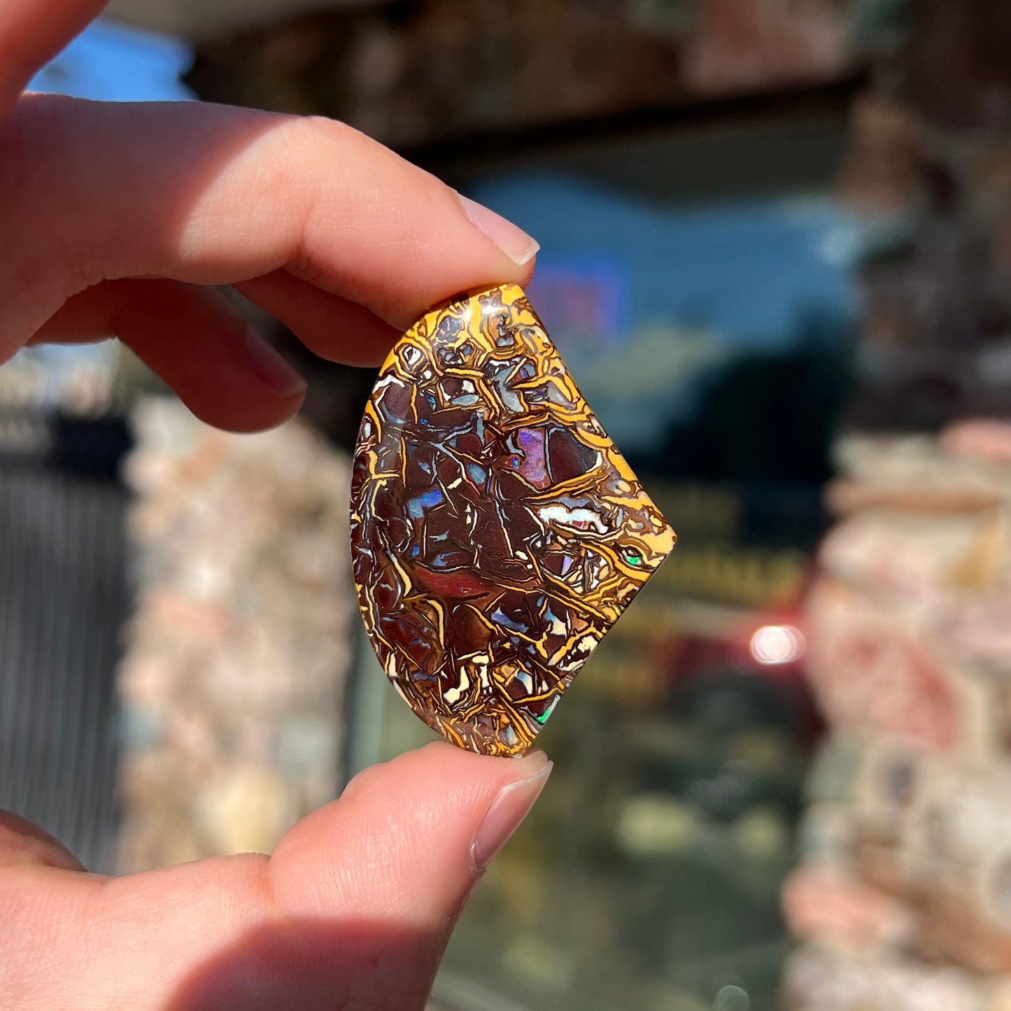 A loose, polished Koroit boulder opal specimen.  The opal has an organic pattern.