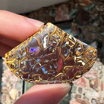 A loose, polished Koroit boulder opal specimen.  The opal has an organic pattern.