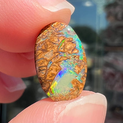 A loose, oval cabochon cut Koroit boulder opal with green fire.