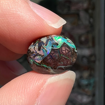 A loose, oval cabochon cut boulder opal stone from Koroit, Australia.  The opal has a bright green flash.