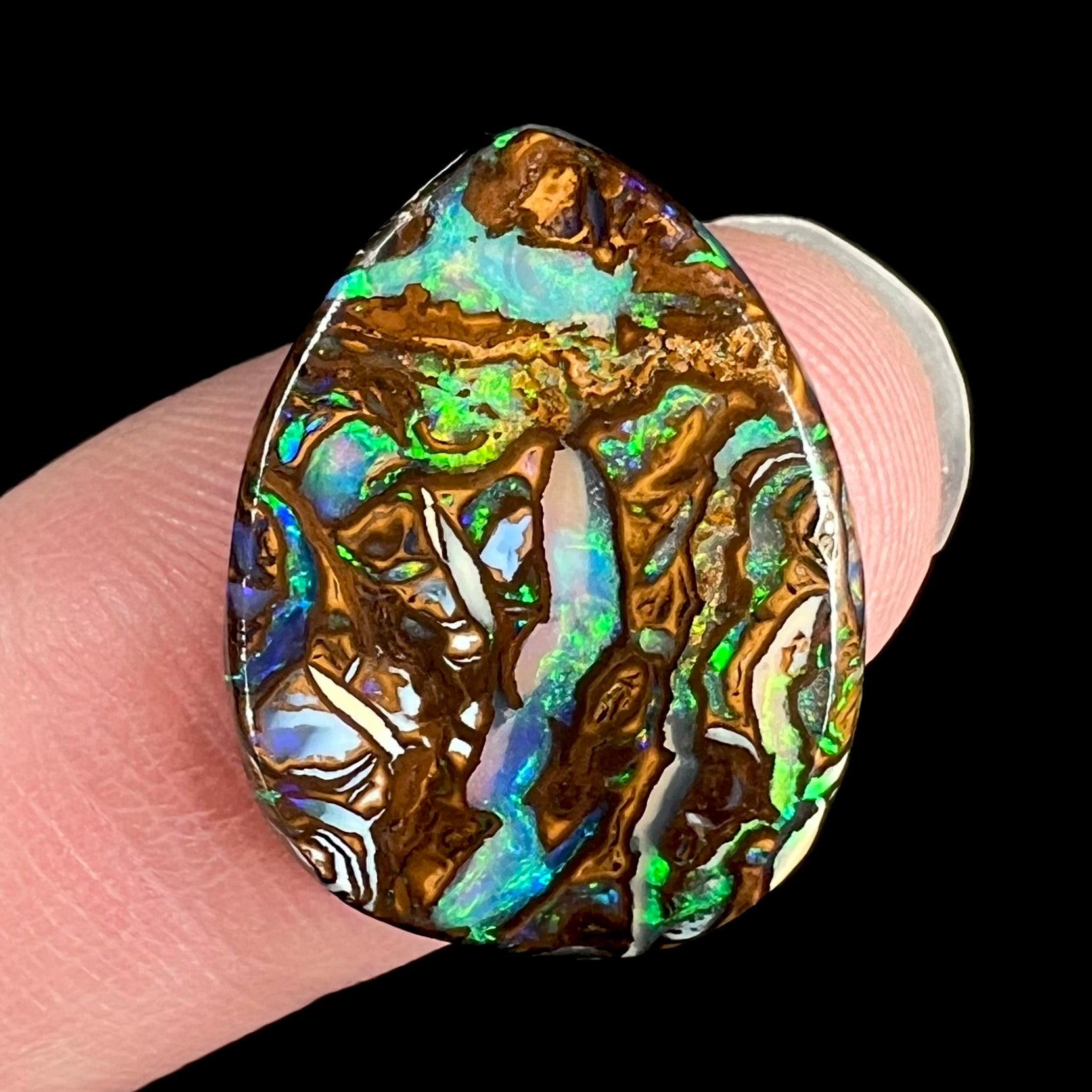 A loose, pear shaped boulder opal stone from Koroit, Australia that has vivd green and blue veins of color.