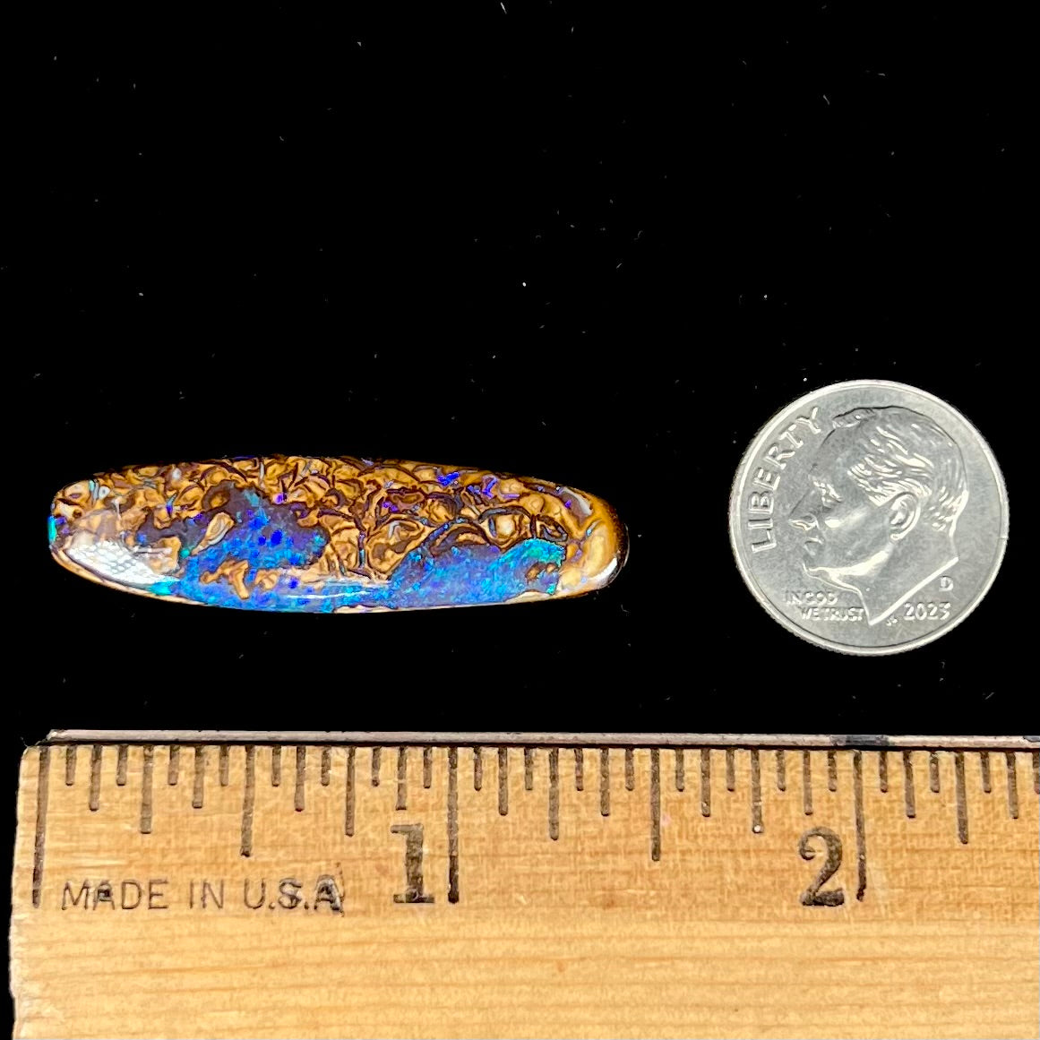 A polished boulder opal stone from Koroit, Australia.  The stone has blue and purple veins.