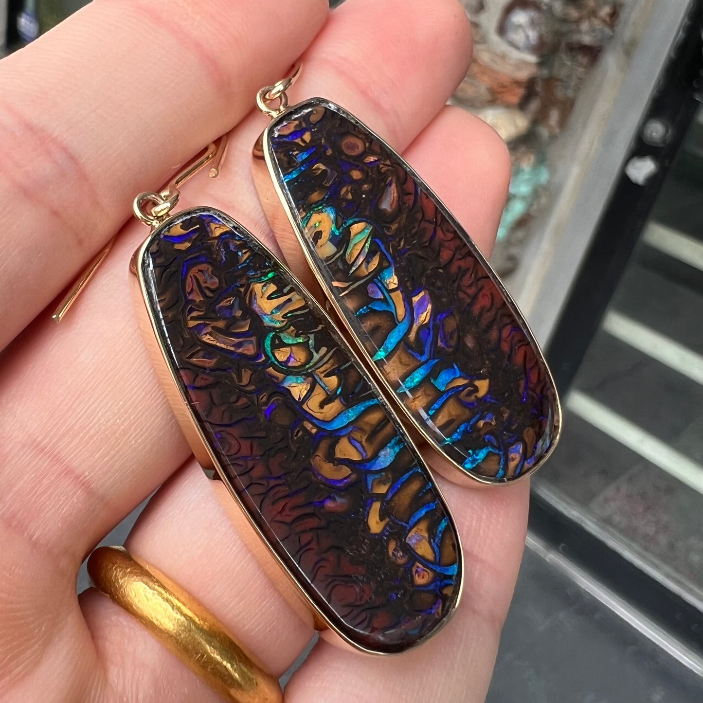 A matched pair of yellow gold patterned boulder opal dangle earrings.  The opals are from Koroit, Australia.