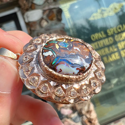 An antique 18 karat yellow gold pendant set with rough diamonds and an oval cut boulder opal from Koroit, Australia.