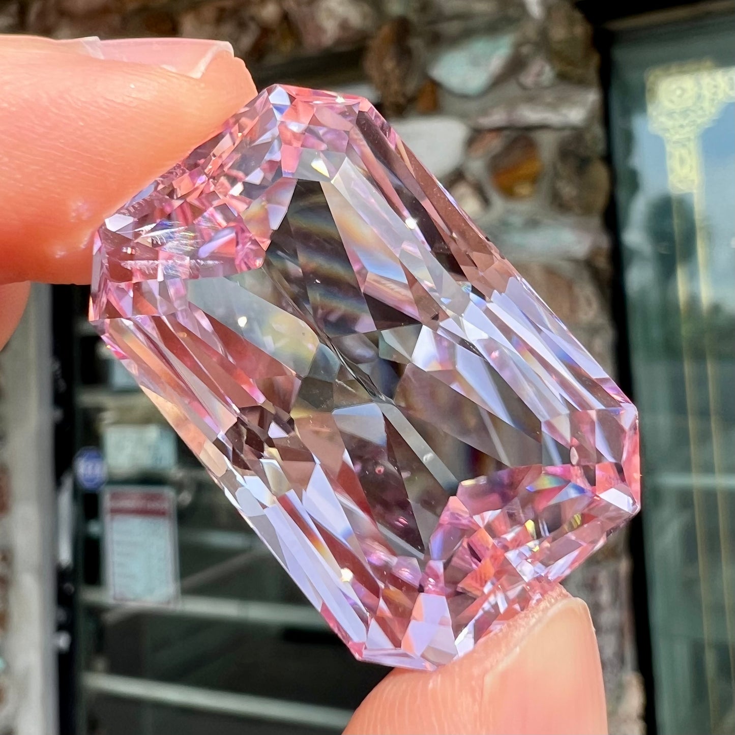 A loose, radiant cut kunzite gemstone.  The stone is a light purplish pink color.