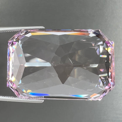 A loose, radiant cut kunzite gemstone.  The stone is a light purplish pink color.