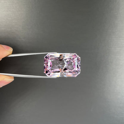 A loose, radiant cut kunzite gemstone.  The stone is a light purplish pink color.