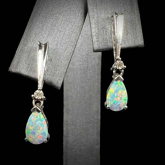 A pair of sterling silver filigree dangle earrings mounted with pear shaped lab created opals and diamond accents.