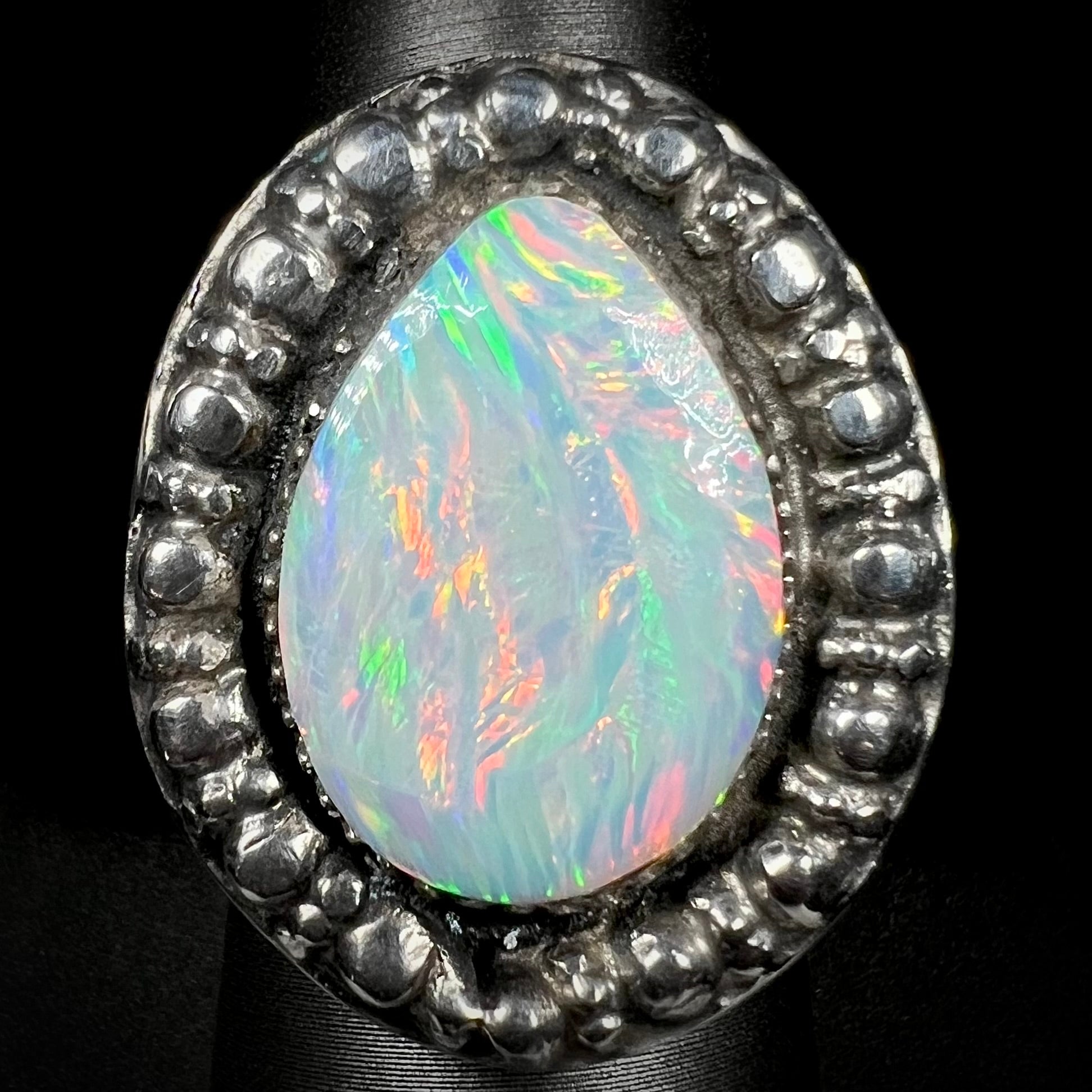 A large sterling silver ring, mounted with a lab created opal stone.