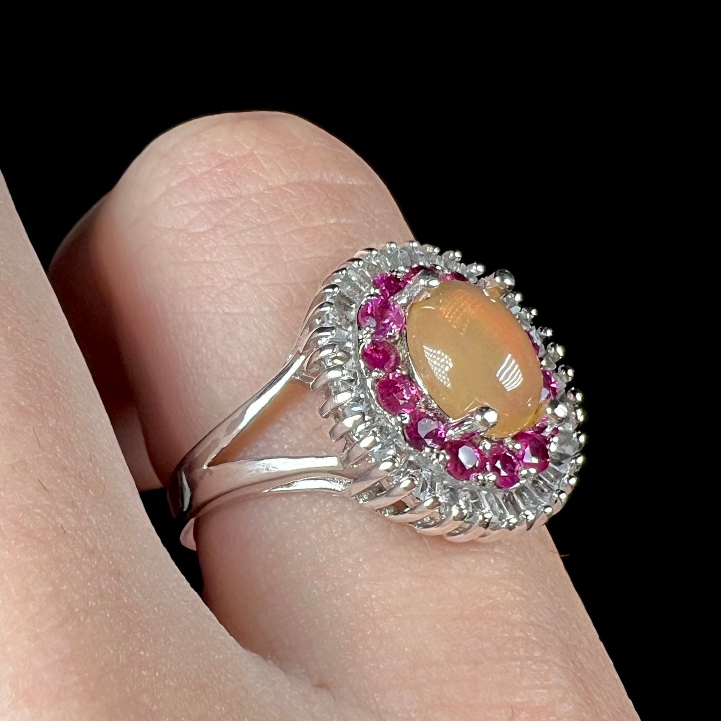 A sterling silver Ethiopian opal ring mounted with a halo of white CZs and another halo of synthetic pink sapphires.