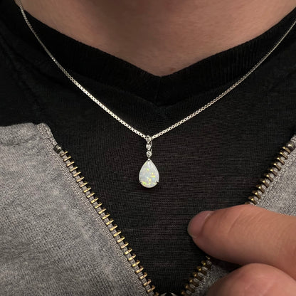 A platinum drop pendant mounted with three diamond accents and a pear shaped opal.