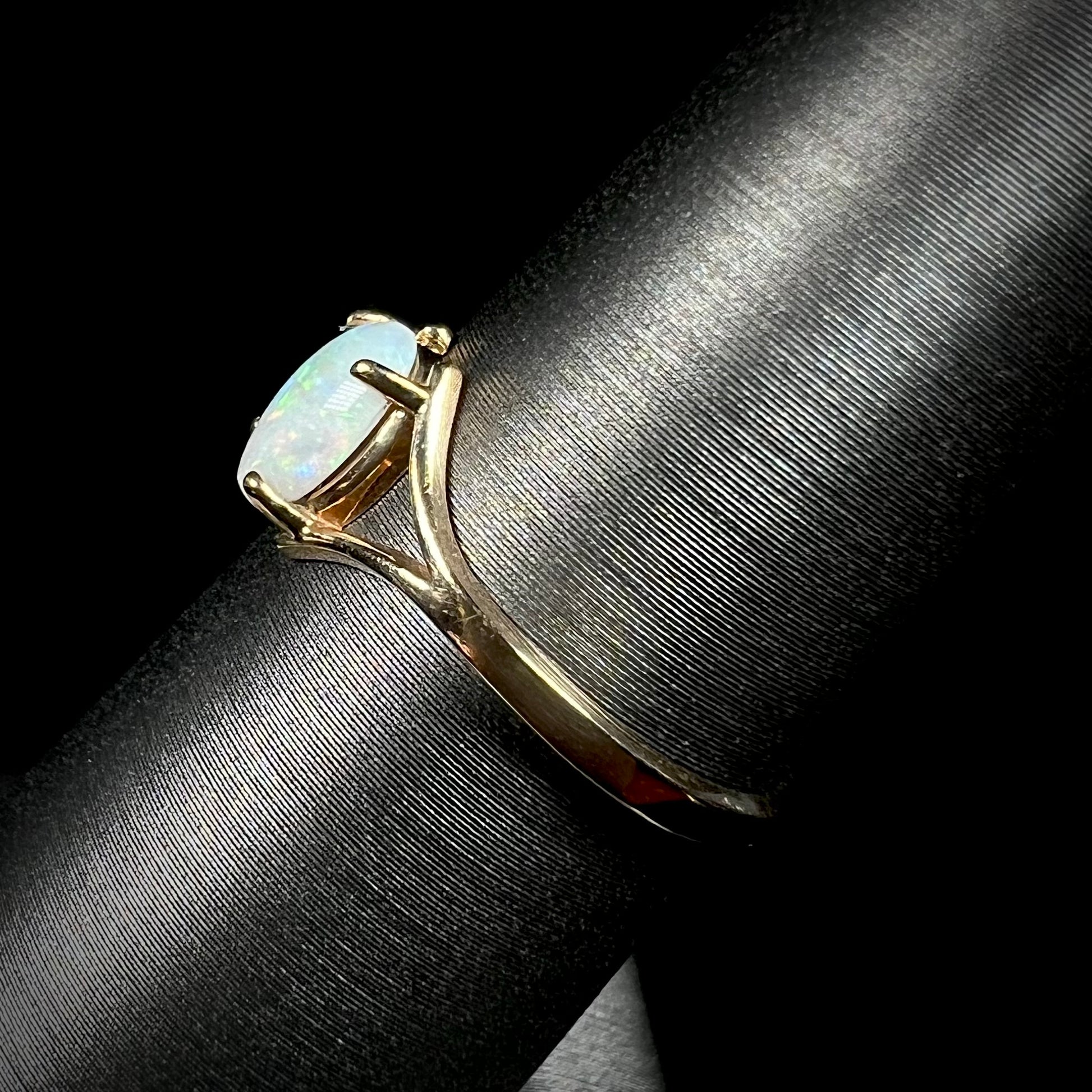 A ladies' simple opal solitaire ring.  The ring is yellow gold with a split shank.