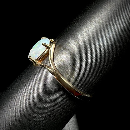 A ladies' simple opal solitaire ring.  The ring is yellow gold with a split shank.