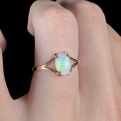 A ladies' simple opal solitaire ring.  The ring is yellow gold with a split shank.