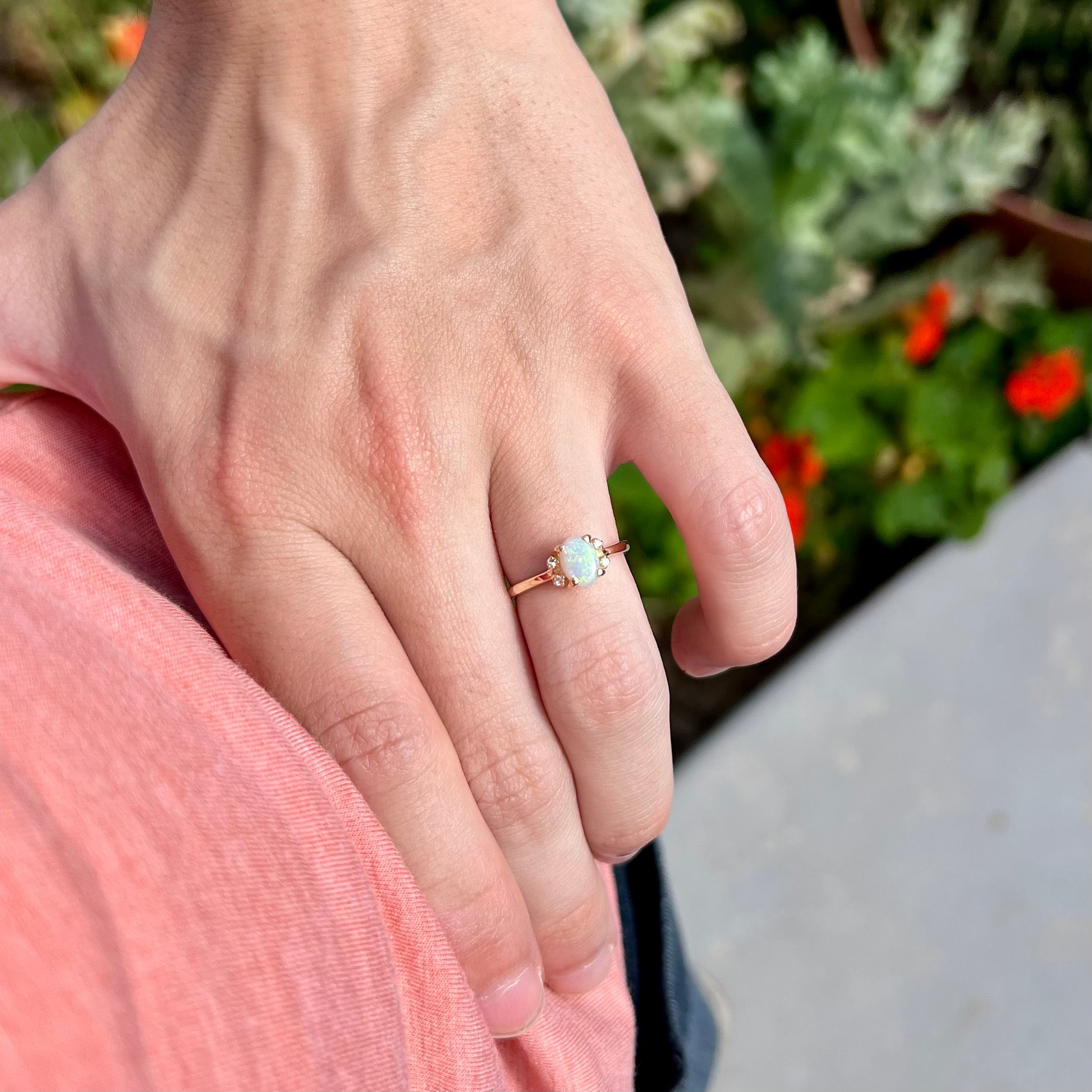 A dainty yellow gold ring set with a Coober Pedy opal with green flashfire pattern and diamond accents.