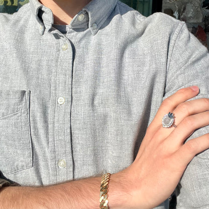 A ladies' white gold ring set with a faceted, heart shaped white moonstone, round moissanites, two aquamarine baguettes, and a marquise cut blue sapphire.