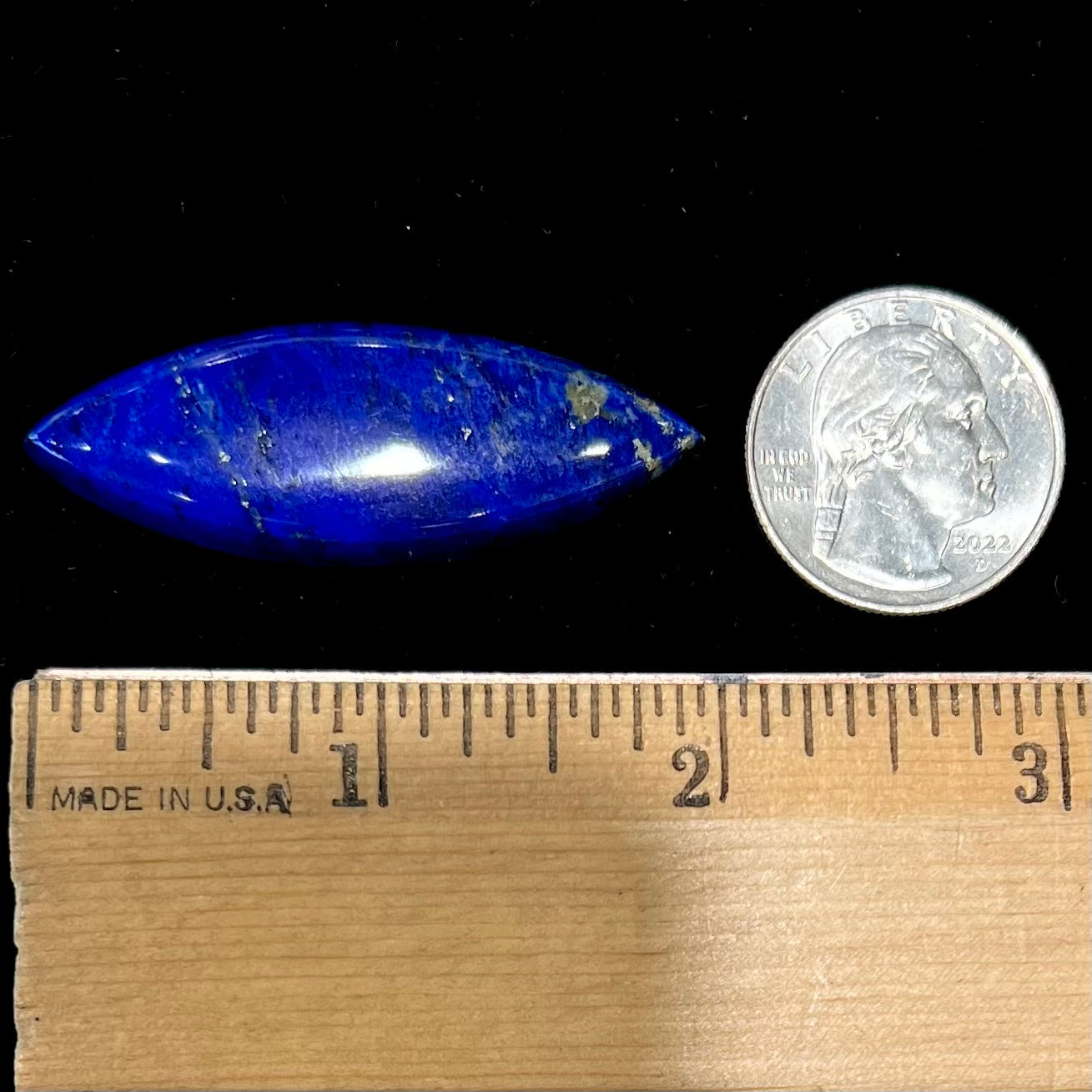 A loose, marquise cabochon cut lapis lazuli stone.  The stone has pyrite inclusions.