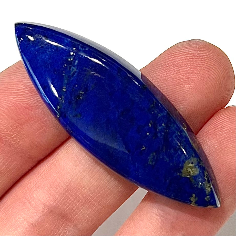 A loose, marquise cabochon cut lapis lazuli stone.  The stone has pyrite inclusions.