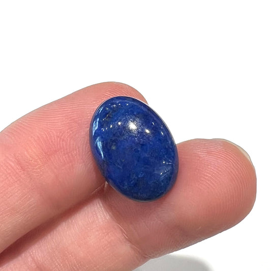 A loose, oval cabochon cut lapis lazuli stone from Blue Mountain, Afghanistan.