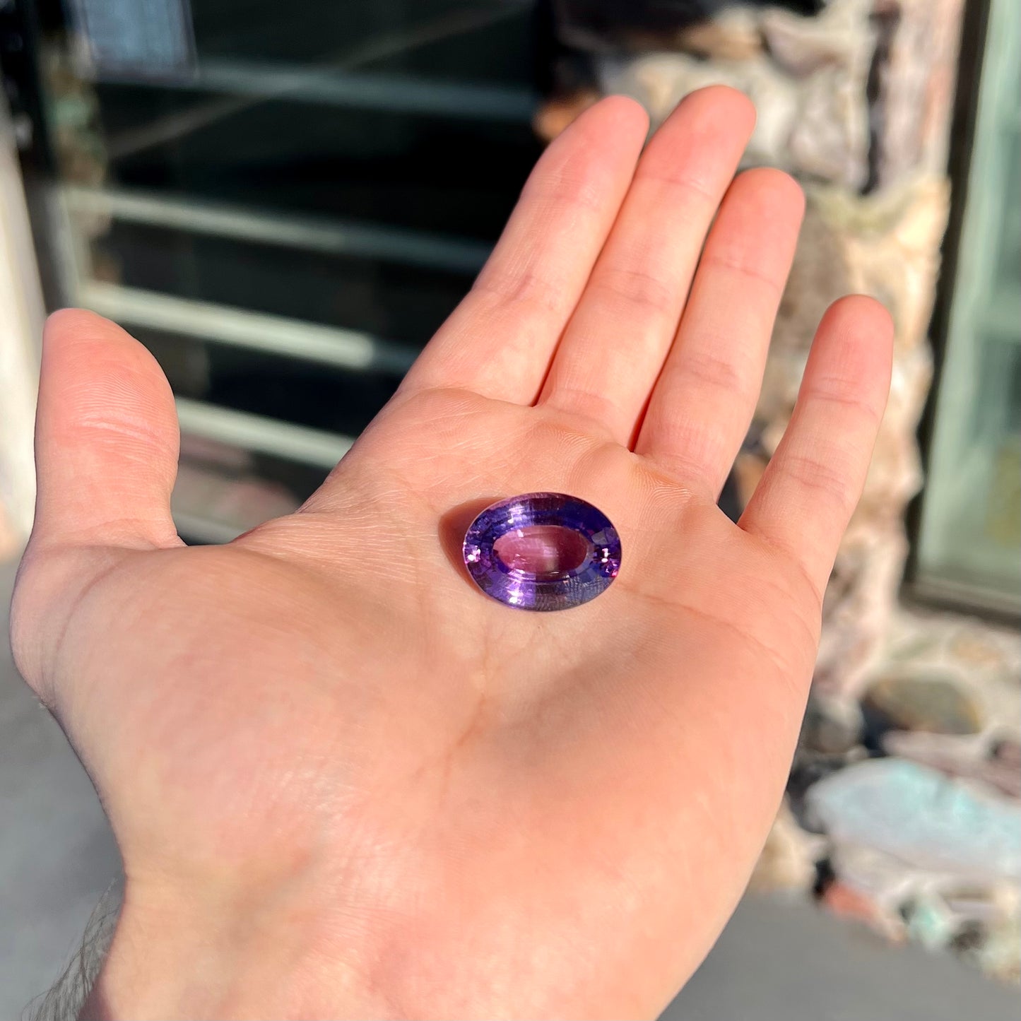 A loose, modified oval step cut amethyst gemstone.  There are light scratches to the table.