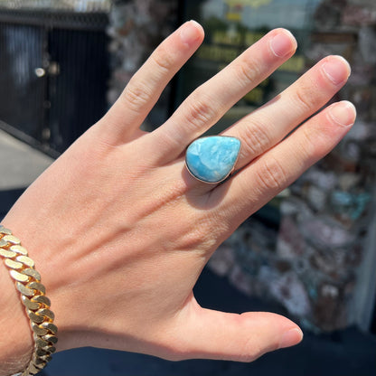 A ladies' large, pear shaped larimar solitaire ring in sterling silver.  The larimar stone measures an inch long.