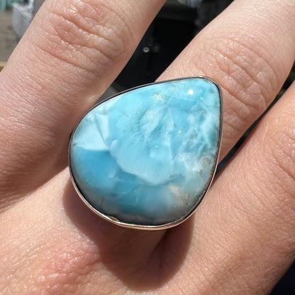 A ladies' large, pear shaped larimar solitaire ring in sterling silver.  The larimar stone measures an inch long.