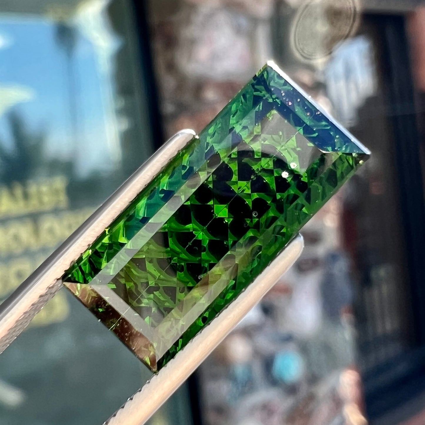 A loose, rectangular laser cut green tourmaline gemstone.