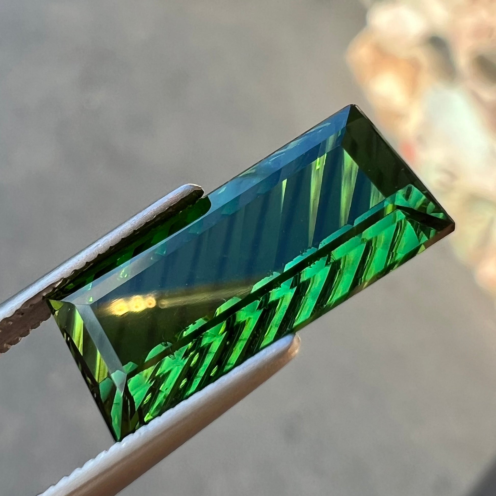 A loose, rectangular laser cut green tourmaline gemstone.