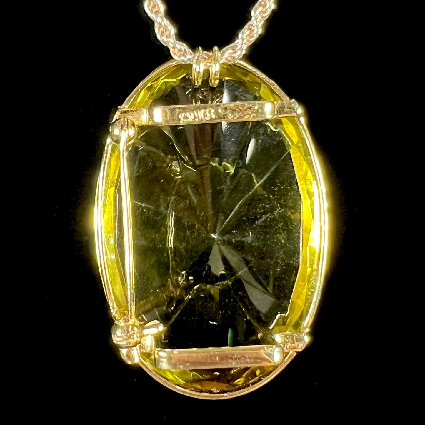 A faceted oval cut lemon quartz gemstone pendant in gold plated sterling silver.  The quartz is a green-yellow color.