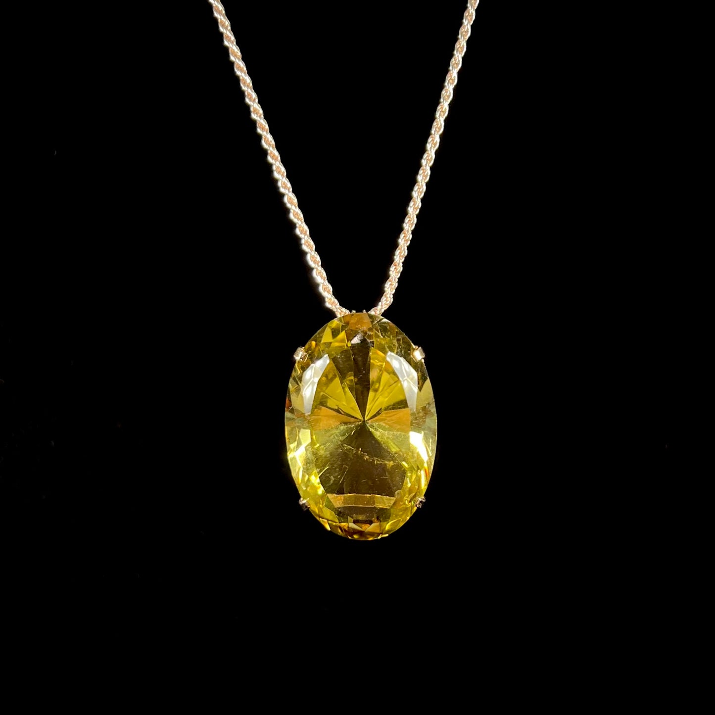 A faceted oval cut lemon quartz gemstone pendant in gold plated sterling silver.  The quartz is a green-yellow color.