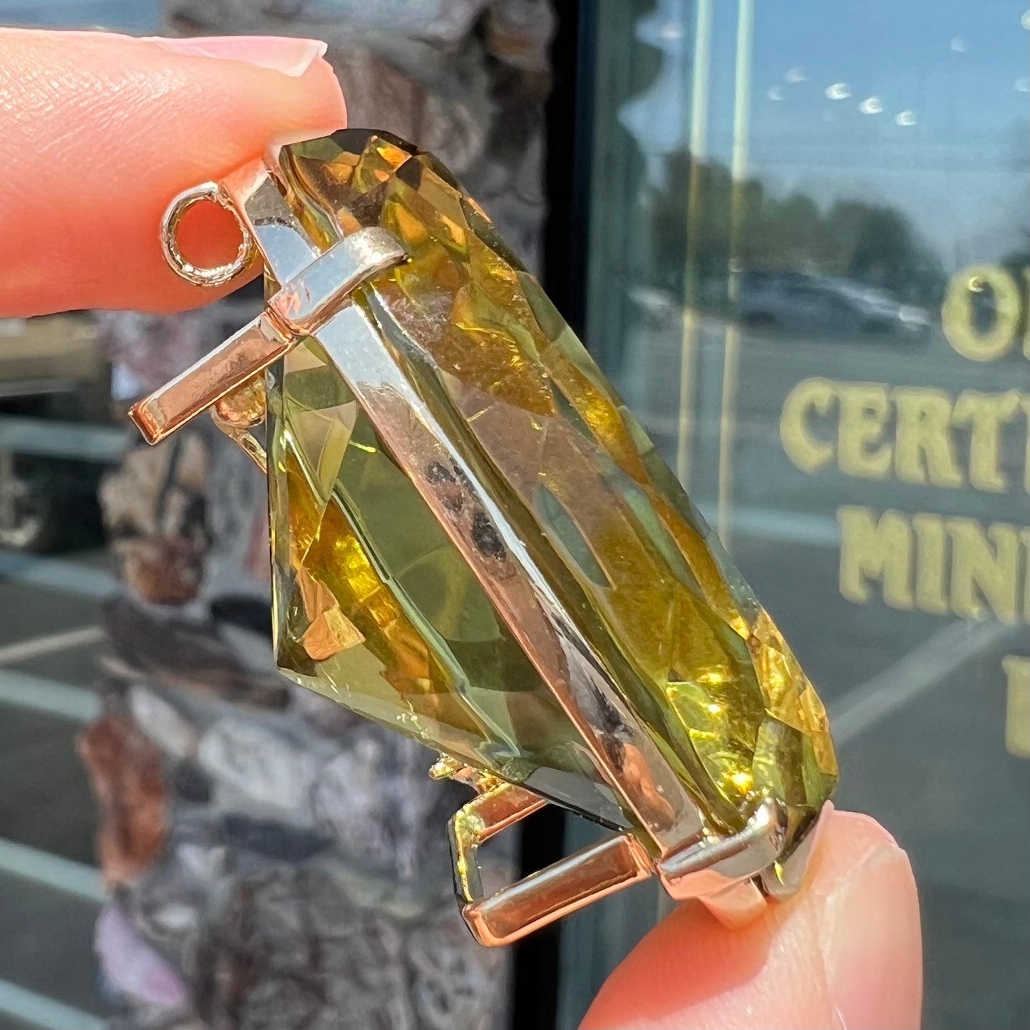 A faceted oval cut lemon quartz gemstone pendant in gold plated sterling silver.  The quartz is a green-yellow color.