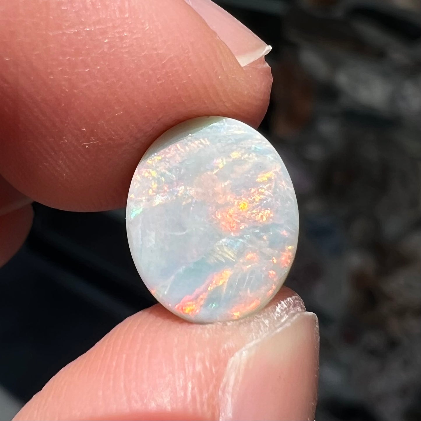 A loose, oval cabochon cut Lightning Ridge light opal stone.