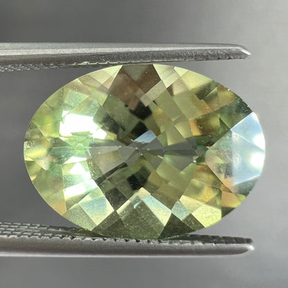 An oval checkerboard cut kiwi mystic topaz gemstone.  The stone is a light yellowish green color.