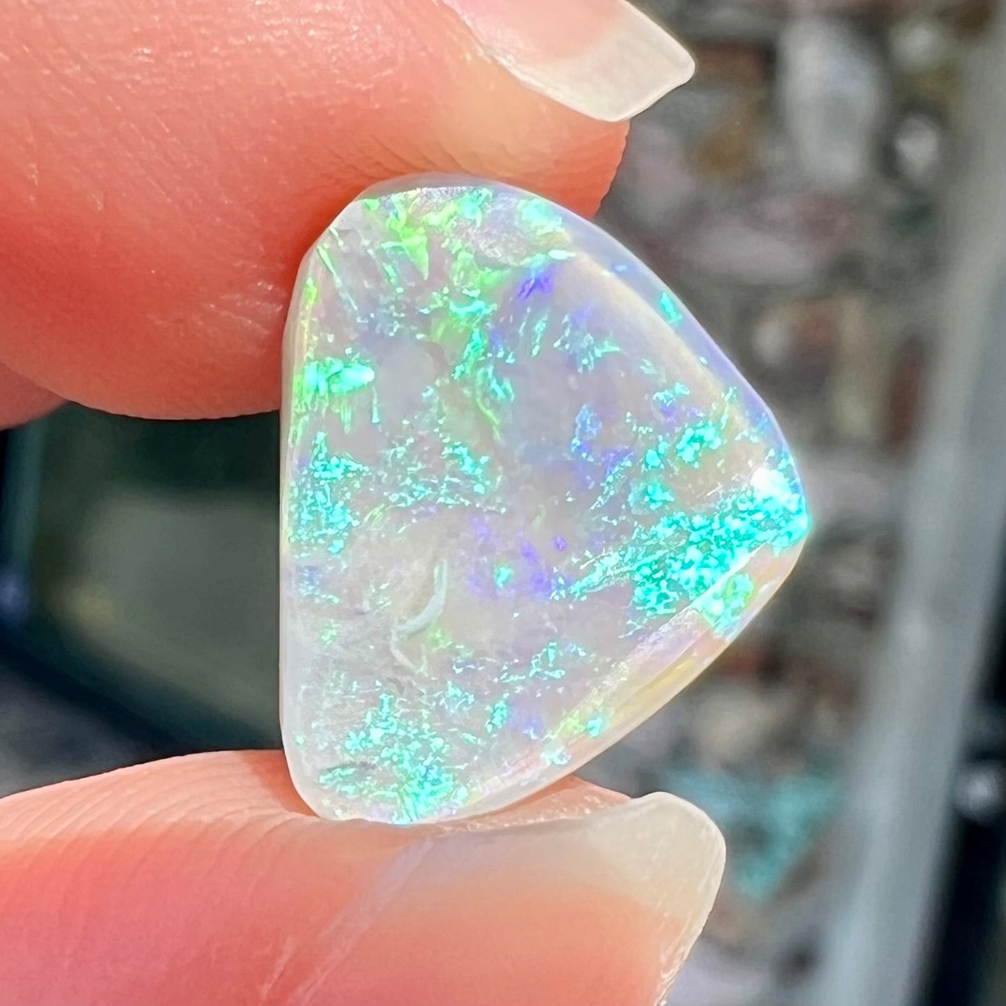 A freeform shaped blue-green light opal stone from Lightning Ridge, Australia.