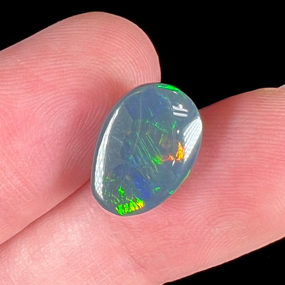 A loose, freeform cut black opal stone from Lightning Ridge, Australia.