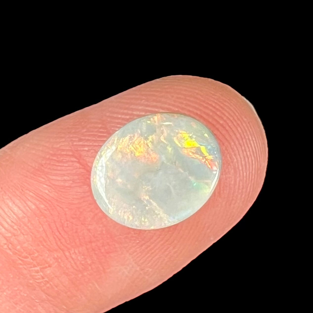 A loose, oval cabochon cut Lightning Ridge light opal stone.