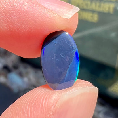 A loose, oval cabochon cut black opal from Lightning Ridge, Australia.  The opal has an N2 body tone.