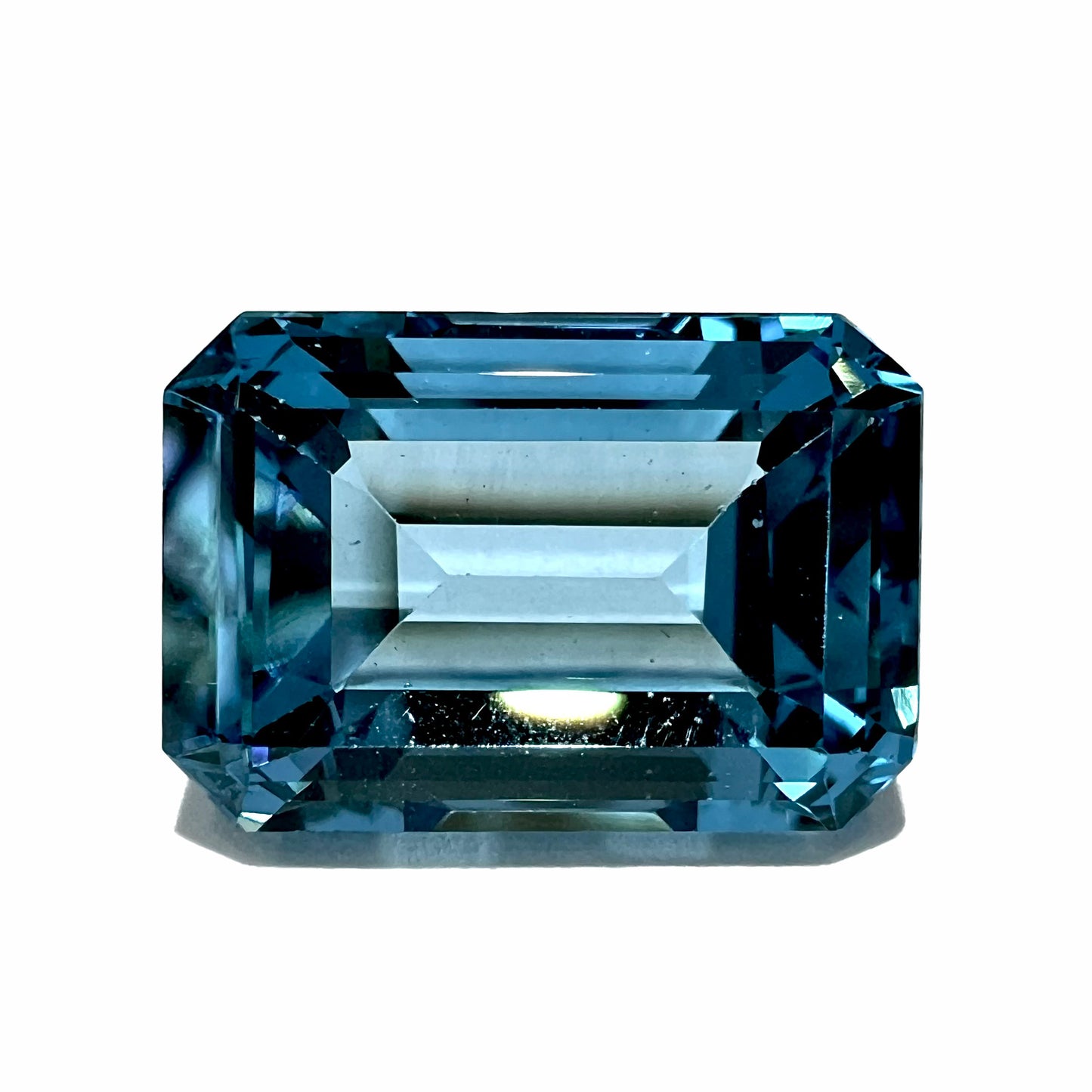 A loose, emerald cut London blue topaz gemstone.  The stone is a deep, dark blue color.