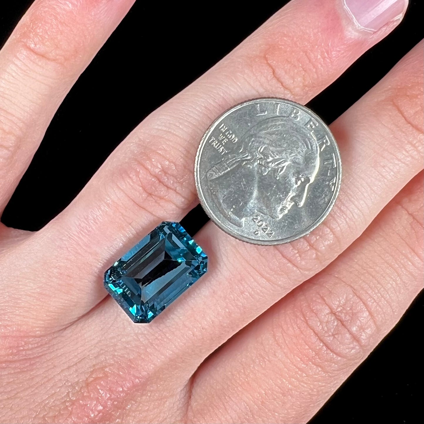 A loose, emerald cut London blue topaz gemstone.  The stone is a deep, dark blue color.