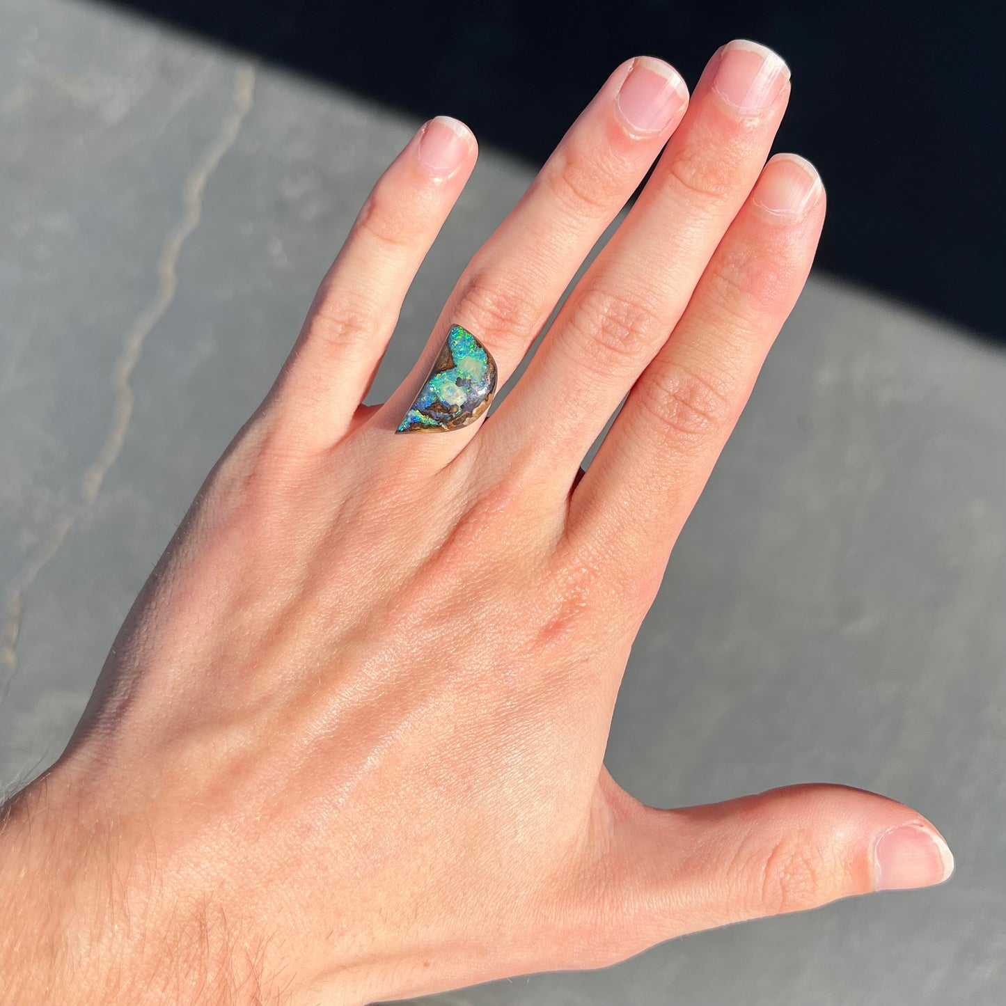 A loose, freeform shaped boulder opal with green and blue multicolor fire from Australia.