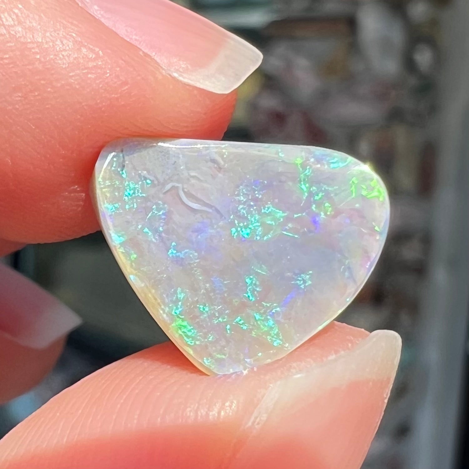 A freeform shaped blue-green light opal stone from Lightning Ridge, Australia.