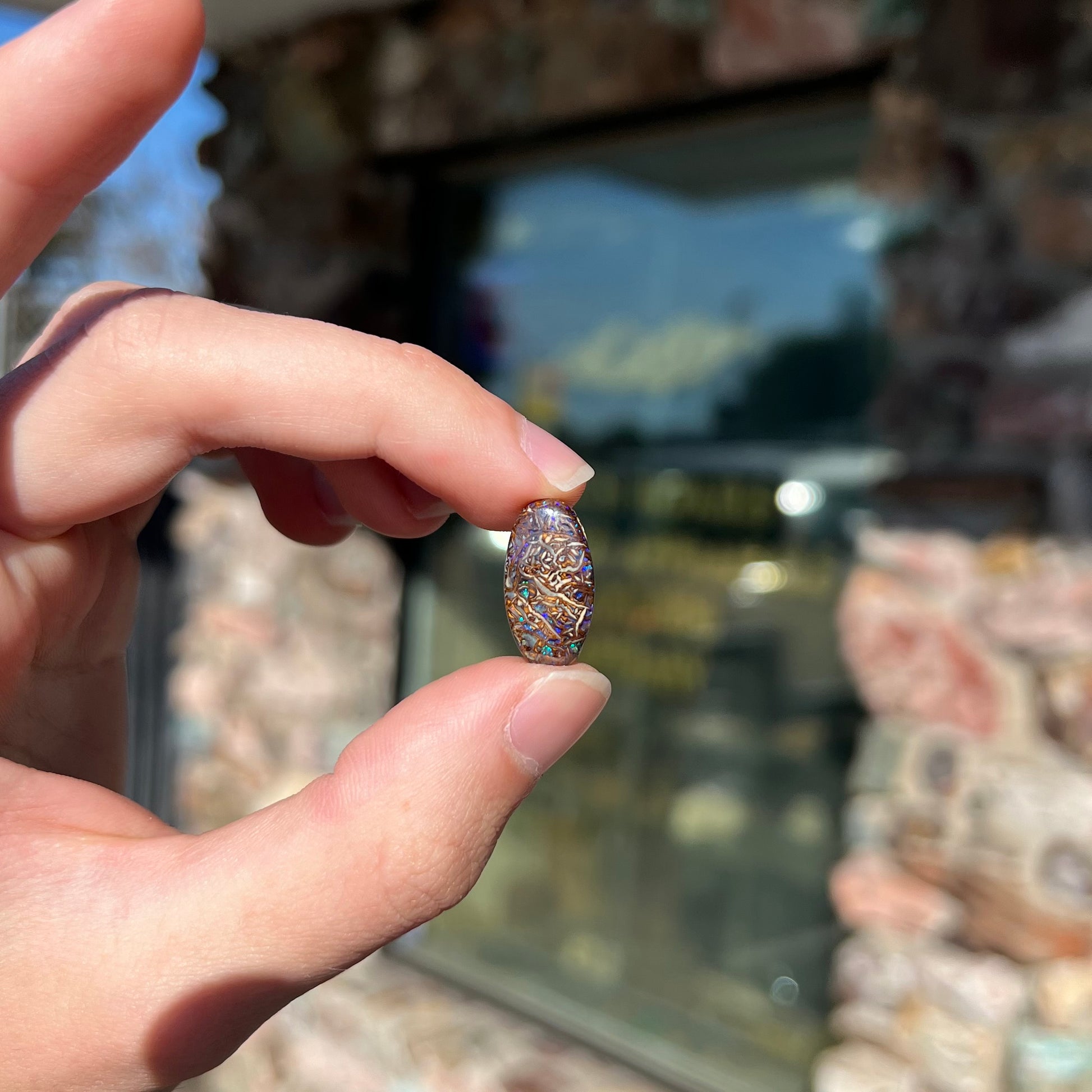 An oval cabochon cut Koroit boulder matrix opal stone.  The opal has blue colors.