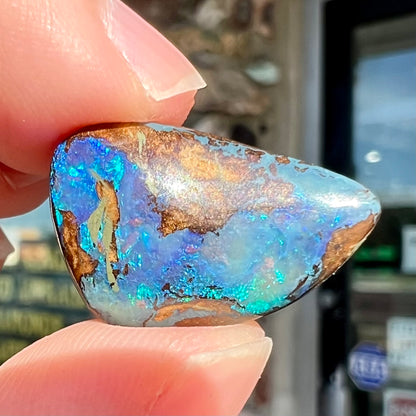 A freeform pear shaped boulder opal stone with blue color.