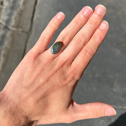 A loose, oval cabochon cut Koroit boulder opal stone.  The opal has green and blue veins.